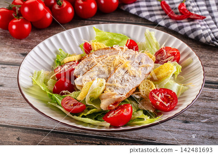 Caesar salad with grilled chicken, parmesan cheese and cherry tomatoes on wooden table Caesar salad with grilled chicken, parmesan cheese and cherry tomatoes on wooden table 142481693