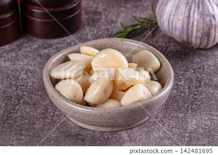 Marinated garlic cloves in a speckled ceramic bowl on a dark grey background Marinated garlic cloves in a speckled ceramic bowl on a dark grey background 142481695