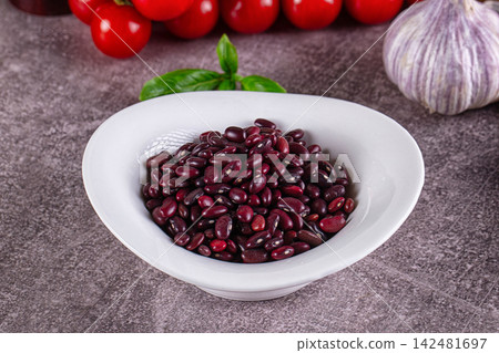 Raw red kidney beans in white bowl with fresh vegetables for cooking Raw red kidney beans in white bowl with fresh vegetables for cooking 142481697