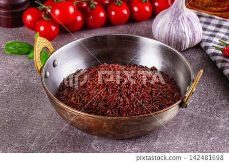 Raw red rice in rustic metal bowl with fresh tomatoes, garlic, and basil 142481698