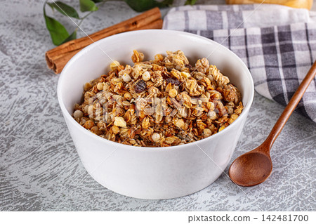Healthy granola breakfast in white bowl with oats, nuts, raisins and cinnamon Healthy granola breakfast in white bowl with oats, nuts, raisins and cinnamon 142481700