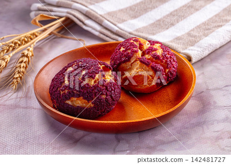 Purple choux au craquelin pastries on wooden plate with wheat Purple choux au craquelin pastries on wooden plate with wheat 142481727