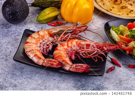 Large cooked tiger prawns on black plate with fresh vegetables and spices Large cooked tiger prawns on black plate with fresh vegetables and spices 142481748