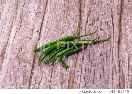 Raw green hot chili peppers on wooden background 142481749