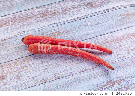 Two fresh red carrots on a light blue wooden background Two fresh red carrots on a light blue wooden background 142481750