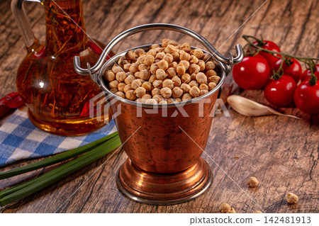 Dried chickpeas in copper bucket, oil bottle, cherry tomatoes, garlic, green onions on wooden surface Dried chickpeas in copper bucket, oil bottle, cherry tomatoes, garlic, green onions on wooden surface 142481913