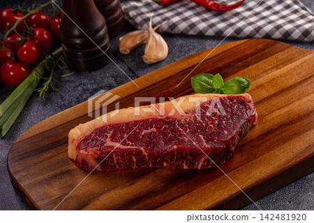 Raw picanha steak on wooden cutting board with tomatoes, garlic, and herbs for cooking Raw picanha steak on wooden cutting board with tomatoes, garlic, and herbs for cooking 142481920