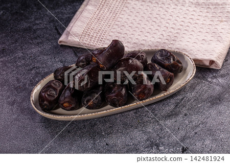 Sweet dried dates in rustic bowl on dark stone background Sweet dried dates in rustic bowl on dark stone background 142481924