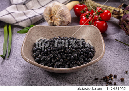 Raw black beans in bowl surrounded by fresh vegetables like garlic, tomato, and artichoke Raw black beans in bowl surrounded by fresh vegetables like garlic, tomato, and artichoke 142481932