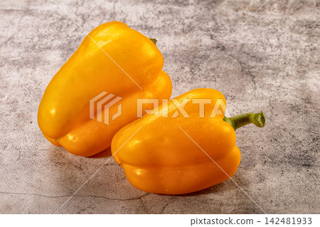 Two fresh yellow bell peppers on textured gray stone background Two fresh yellow bell peppers on textured gray stone background 142481933
