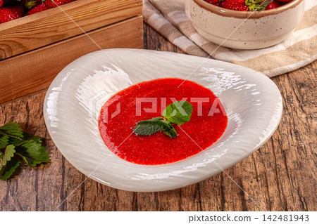 Cold strawberry soup with mint garnish in white bowl on rustic wood table Cold strawberry soup with mint garnish in white bowl on rustic wood table 142481943