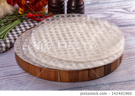 Dry rice paper wrappers for spring rolls on wooden board with fresh herbs and spices Dry rice paper wrappers for spring rolls on wooden board with fresh herbs and spices 142481960
