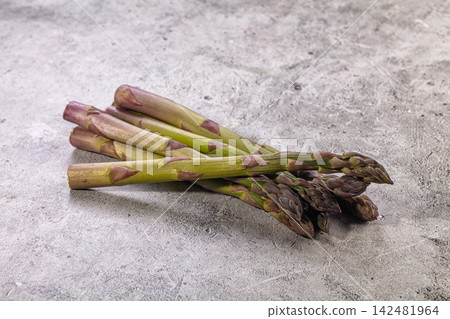 Fresh raw green asparagus spears with purple tips on grey textured background Fresh raw green asparagus spears with purple tips on grey textured background 142481964
