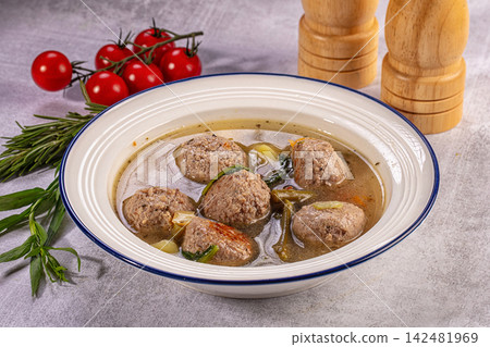Homemade meatball soup with fresh vegetables in white bowl with cherry tomatoes and rosemary Homemade meatball soup with fresh vegetables in white bowl with cherry tomatoes and rosemary 142481969