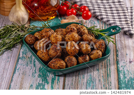 Roasted baby potatoes with rosemary, garlic, and tomatoes on rustic wooden table Roasted baby potatoes with rosemary, garlic, and tomatoes on rustic wooden table 142481974
