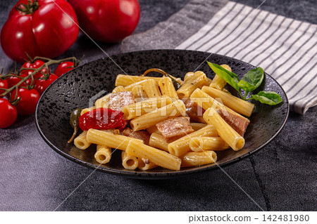 Rigatoni pasta with tuna, sun dried tomatoes, and capers in rustic black bowl Rigatoni pasta with tuna, sun dried tomatoes, and capers in rustic black bowl 142481980