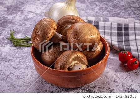 Fresh brown mushrooms in terracotta bowl with garlic rosemary and cherry tomatoes on rustic surface Fresh brown mushrooms in terracotta bowl with garlic rosemary and cherry tomatoes on rustic surface 142482015