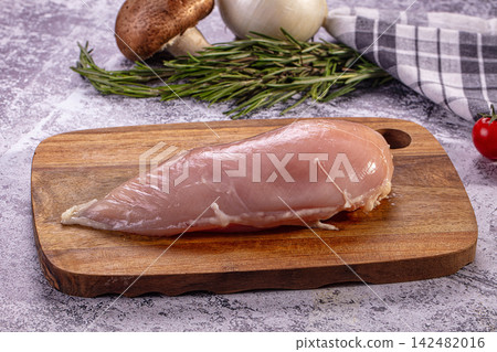 Raw chicken breast on wooden cutting board with rosemary mushrooms and onion Raw chicken breast on wooden cutting board with rosemary mushrooms and onion 142482016