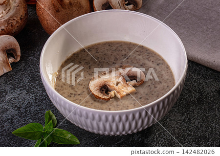 Creamy mushroom soup in white bowl with fresh champignons and basil 142482026
