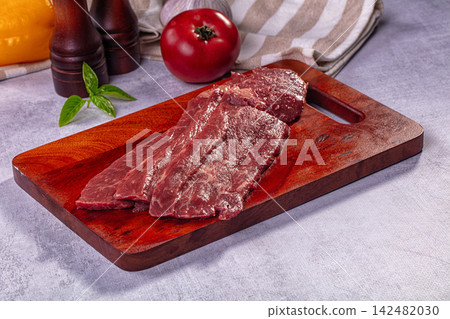 Raw beef steak on wooden cutting board with fresh vegetables and spices Raw beef steak on wooden cutting board with fresh vegetables and spices 142482030