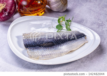 Salted herring fillets on white plate with onion and garlic Salted herring fillets on white plate with onion and garlic 142482044