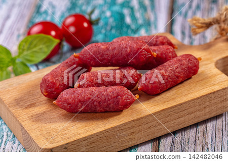 Mini piccolini salami sausages on wooden cutting board with cherry tomatoes Mini piccolini salami sausages on wooden cutting board with cherry tomatoes 142482046