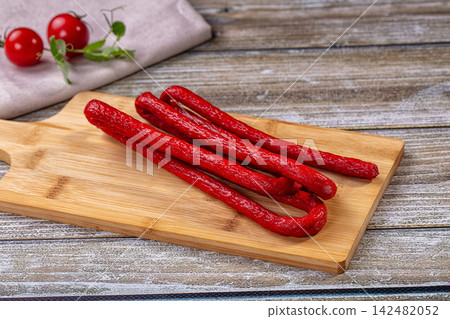 Mini salami sausages on wooden cutting board with cherry tomatoes Mini salami sausages on wooden cutting board with cherry tomatoes 142482052