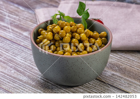Canned green peas with fresh sprouts in rustic ceramic bowl on wooden table Canned green peas with fresh sprouts in rustic ceramic bowl on wooden table 142482053