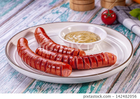 Roasted sausages with mustard sauce on white plate on rustic wooden table Roasted sausages with mustard sauce on white plate on rustic wooden table 142482056
