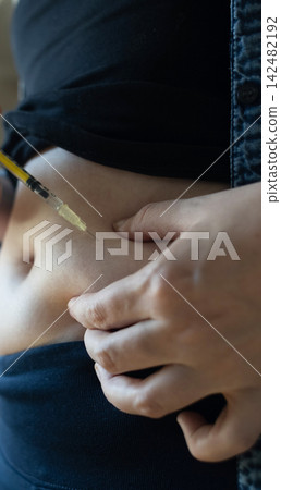Woman making hormone injection into belly at home for ivf fertility treatment and ovulation stimulation. Concept of reproductive medicine, hormone therapy, and subcutaneous injection. 142482192
