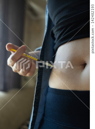 Woman making hormone injection into belly at home for ivf fertility treatment and ovulation stimulation. Concept of reproductive medicine, hormone therapy, and subcutaneous injection. 142482193