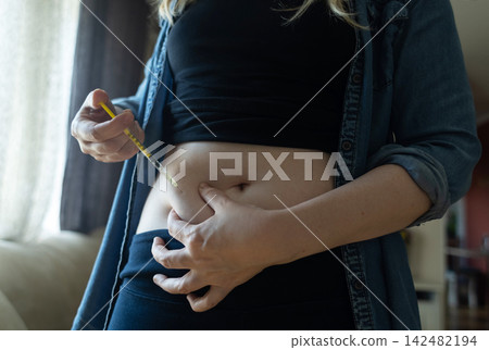 Woman making hormone injection into belly at home for ivf fertility treatment and ovulation stimulation. Concept of reproductive medicine, hormone therapy, and subcutaneous injection. Woman making hormone injection into belly at home for ivf fertility treatment and ovulation stimulation. Concept of reproductive medicine, hormone therapy, and subcutaneous injection. 142482194