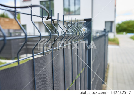 Metal mesh fence with privacy screen beside modern residential property Metal mesh fence with privacy screen beside modern residential property 142482567