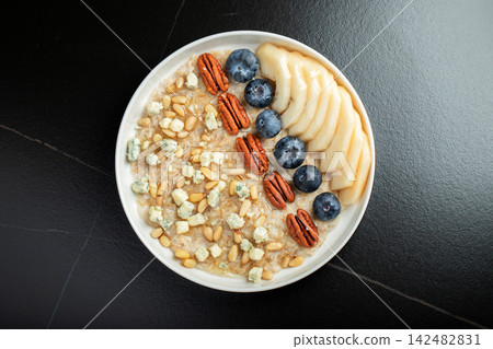 Oatmeal. Bowl of oatmeal porridge with blackberry, bananas and chia seeds on gray concrete old table background. Top view in flat lay style. Natural ingredients. Hot healthy breakfast and diet food Oatmeal. Bowl of oatmeal porridge with blackberry, bananas and chia seeds on gray concrete old table background. Top view in flat lay style. Natural ingredients. Hot healthy breakfast and diet food 142482831