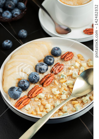 Oatmeal. Bowl of oatmeal porridge with blackberry, bananas and chia seeds on gray concrete old table background. Top view in flat lay style. Natural ingredients. Hot healthy breakfast and diet food Oatmeal. Bowl of oatmeal porridge with blackberry, bananas and chia seeds on gray concrete old table background. Top view in flat lay style. Natural ingredients. Hot healthy breakfast and diet food 142482832