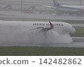 一架客機降落在下著雨的跑道上，引擎的反推力噴出一股水柱。 142482862