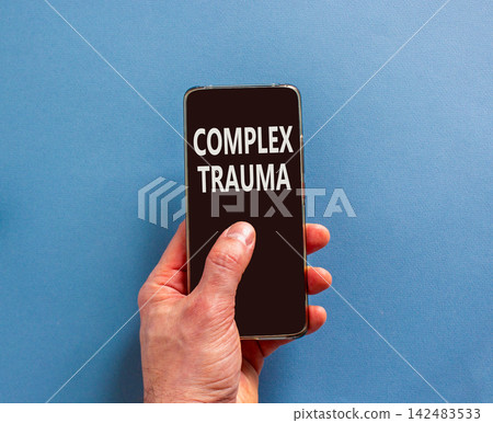Complex trauma words symbol. Concept words Complex trauma on beautiful black mobile phone screen. Beautiful blue background. Psychologist hand. Psychological complex trauma support concept. Copy space Complex trauma words symbol. Concept words Complex trauma on beautiful black mobile phone screen. Beautiful blue background. Psychologist hand. Psychological complex trauma support concept. Copy space 142483533