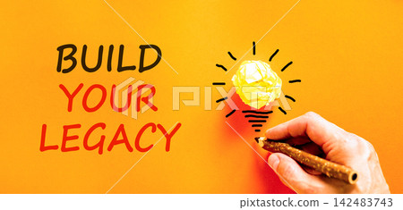 Build your legacy words symbol. Concept words Build your legacy on beautiful orange paper. Beautiful orange background. Businessman hand. Business build your legacy concept. Copy space. Build your legacy words symbol. Concept words Build your legacy on beautiful orange paper. Beautiful orange background. Businessman hand. Business build your legacy concept. Copy space. 142483743