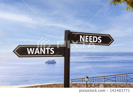 Needs instead wants words symbol. Concept words Needs Wants on beautiful black road sign. Beautiful blue sky background. Business psychology needs or wants concept. Copy space. Needs instead wants words symbol. Concept words Needs Wants on beautiful black road sign. Beautiful blue sky background. Business psychology needs or wants concept. Copy space. 142483771