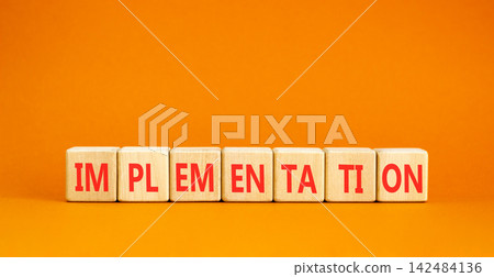 Implementation word symbol. Concept word Implementation on beautiful wooden blocks. Beautiful orange table orange background. Business implementation word concept. Copy space. Implementation word symbol. Concept word Implementation on beautiful wooden blocks. Beautiful orange table orange background. Business implementation word concept. Copy space. 142484136