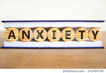 Anxiety word symbol. Concept word Anxiety on beautiful wooden circles in book. Beautiful wooden table white background. Business medical anxiety word concept. Copy space. Anxiety word symbol. Concept word Anxiety on beautiful wooden circles in book. Beautiful wooden table white background. Business medical anxiety word concept. Copy space. 142484799