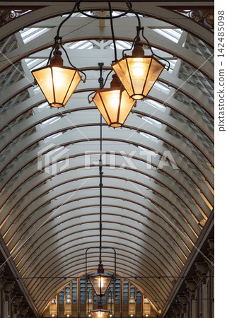 The spectacular victorian architecture of the ornate wrought-iron, glass roof and hanging lantern within Leadenhall Market. The spectacular victorian architecture of the ornate wrought-iron, glass roof and hanging lantern within Leadenhall Market. 142485098