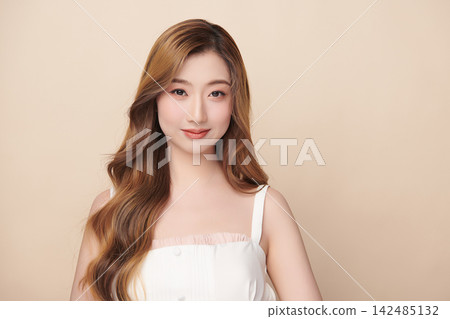 A beautiful young Asian woman with clean, fresh skin against a beige background. Skincare, facial treatment, cosmetology, beauty, and spa. An elegant portrait of an Asian woman. A beautiful young Asian woman with clean, fresh skin against a beige background. Skincare, facial treatment, cosmetology, beauty, and spa. An elegant portrait of an Asian woman. 142485132