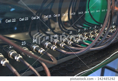Braided cables inserted in device for testing battery cells of electric vehicles at special workshop Braided cables inserted in device for testing battery cells of electric vehicles at special workshop 142485292