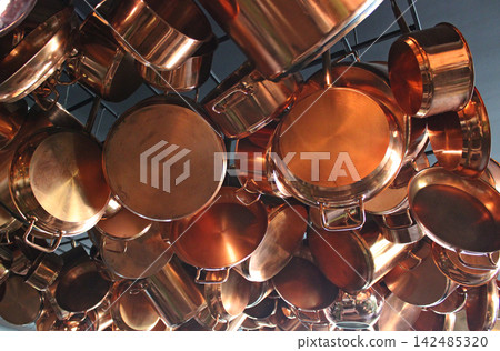 A pattern of stylish traditional shiny polished copper kitchen pans and pots A pattern of stylish traditional shiny polished copper kitchen pans and pots 142485320