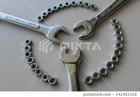 Triple Connection Of Chrome Wrenches Inside Ring Of Steel Hex Nuts Isolated On White Industrial Surface 142485328