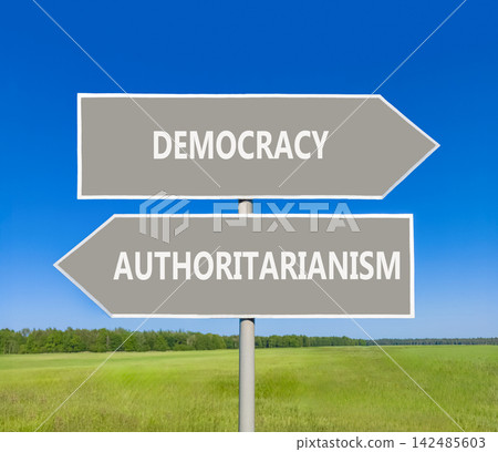 Democracy or authoritarianism symbol. Concept words Democracy Authoritarianism on beautiful grey road sign. Beautiful blue sky background. Business democracy authoritarianism concept. Copy space 142485603