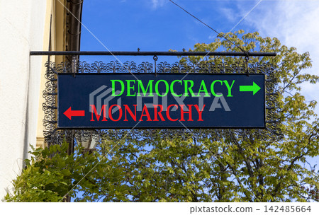 Democracy or monarchy words symbol. Concept words Democracy Monarchy on beautiful black road sign. Beautiful blue sky background. Business democracy monarchy concept. Copy space Democracy or monarchy words symbol. Concept words Democracy Monarchy on beautiful black road sign. Beautiful blue sky background. Business democracy monarchy concept. Copy space 142485664