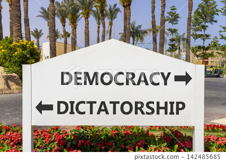 Democracy or dictatorship words symbol. Concept words Democracy Dictatorship on beautiful white road sign. Beautiful palm trees background. Business democracy dictatorship concept. Copy space Democracy or dictatorship words symbol. Concept words Democracy Dictatorship on beautiful white road sign. Beautiful palm trees background. Business democracy dictatorship concept. Copy space 142485685