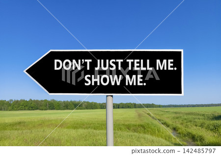 Tell or show symbol. Concept words Do not just tell me, show me beautiful black road sign. Beautiful blue sky green field background. Business tell or show concept. Copy space. Tell or show symbol. Concept words Do not just tell me, show me beautiful black road sign. Beautiful blue sky green field background. Business tell or show concept. Copy space. 142485797